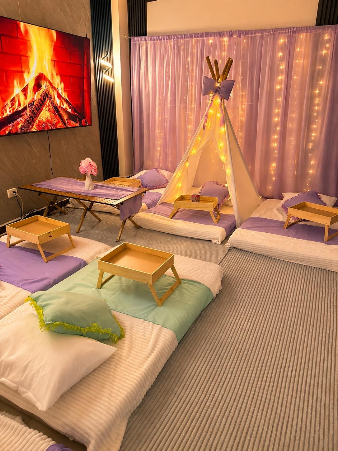 Pijamada Cony Decora con varios puestos, mesas desayunadoras de madera, teepee con luces y cortina morada